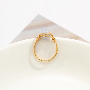 Detailed view of handmade gold wire-wrapped ring with a translucent light blue gemstone