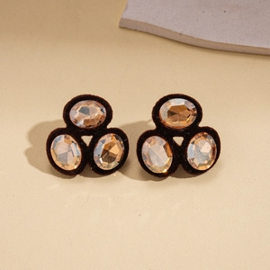 Close-up of vintage oval flocked earrings with amber crystal stones on stone surface