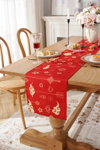 Detail of red festive table runner with traditional gold patterns on a wooden table