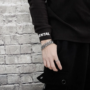Gros plan d'un bracelet gourmette argenté en acier de style punk sur le poignet d'un homme