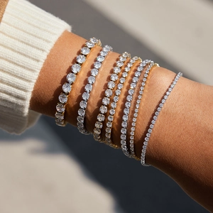 Dettaglio di bracciali tennis sovrapposti in oro e argento con zirconi sul polso