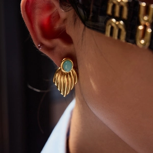 Close-up of vintage gold fan-shaped earrings with light blue oval gemstone on model