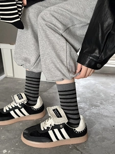 Close-up of black retro sneakers with white stripes and vintage gum sole on street pavement