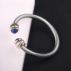 Detail of silver twisted cable bracelet featuring blue stones and gold accent rings
