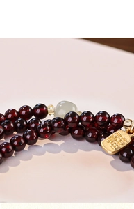 Detailed macro view of multi-layer red garnet beads with jade charm and gold Fu tag