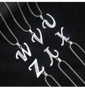 Detailed view of silver stainless steel alphabet pendants with sparkling zircon inlays