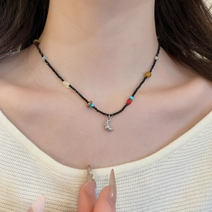 Detail of beaded gemstone necklace with metallic shell pendant on model neck