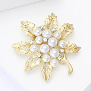 Close-up of golden leaf brooch with white pearls and sparkling rhinestones detail