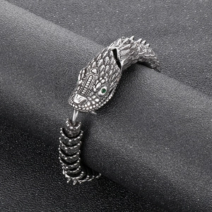 Close-up of retro dragon scale bracelet with green eye inlay and vintage silver finish