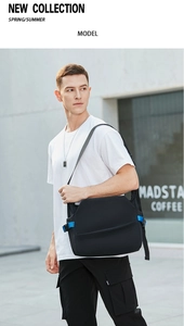 Outdoor shot of a black messenger bag with blue strap on a male model in the city