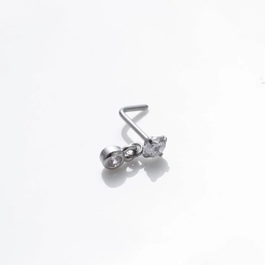 Gros plan d'un piercing nez en forme de L argenté avec double zircon transparent