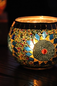 Macro view of blue mosaic glass candle holder with glowing sunflower pattern detail