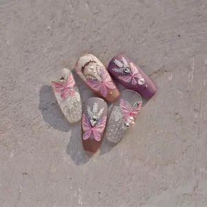 Detail view of pink butterfly and lace press-on nails with pearl and rhinestone accents