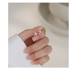 Macro shot of a shimmering s925 silver star earring with zircon held by a hand