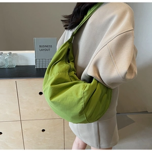 Close-up of green nylon dumpling bag showing soft pleated texture and large capacity size
