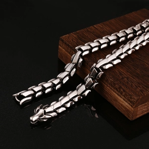 Détail de la chaîne d'os de dragon en acier inoxydable argenté sur bois sombre