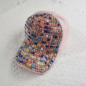 Close-up of pink baseball cap with colorful pearls and sparkling rhinestone embellishments