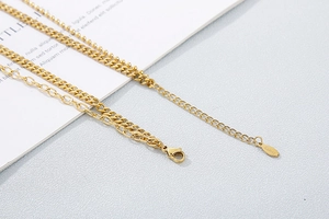 Detail of gold multi-layer stainless steel necklace featuring bead and flat chains