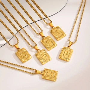 Colliers en acier inoxydable doré avec pendentifs carrés à lettres sur un fond blanc épuré