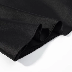 Détail macro du tissu en satin noir montrant une texture lisse et un drapé élégant