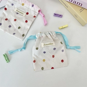 Flat lay of colorful polka dot cotton drawstring pouches with Sozakka brand labels