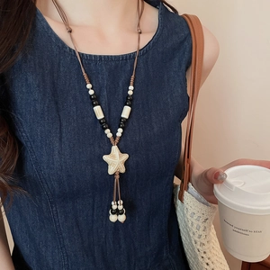 Detail of a ceramic starfish pendant necklace on a braided rope with fringe