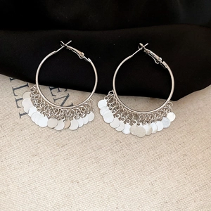 Detail of silver layered sequin tassel hoop earrings on black silk and canvas fabric