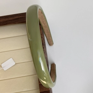Detail showing grass green glossy headband with brown non-slip inner lining on wooden tray