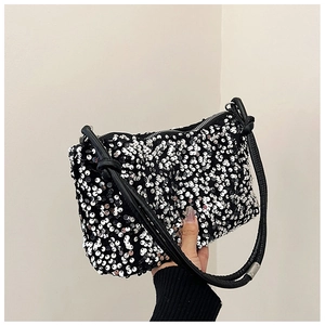 Detailed macro view of silver sequins on a black bag with a knotted strap handle