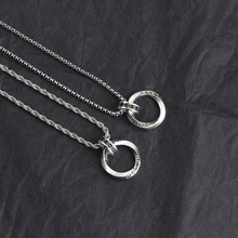 Detailed shot of silver box and twist chains with circular pendant on grey background