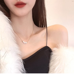 Close-up of minimalist gold pearl necklace worn by a model in French vintage style