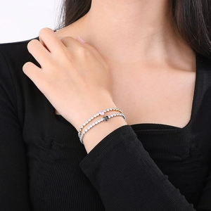 Detail of stacked gold and silver heart bracelets with sparkling pavé stones on a wrist
