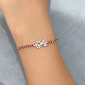 Close-up of heart bow bracelet with pink and clear zircons on a silver chain