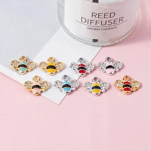 Colorful bumblebee pendants with crystal wings and enamel details on a pink background