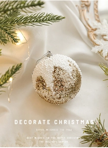 Vue détaillée d'une boule de Noël en mousse avec paillettes dorées et texture de neige