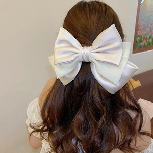Close-up of a large champagne satin bow hair clip with a layered structure on hair
