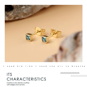 Macro detail of square blue zircon earrings with gold plating and minimalist setting
