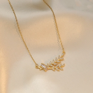 Elegant gold leaf pendant necklace with zircon crystals on a soft silk background