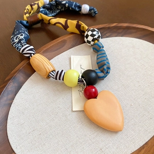 Détail du collier bohème avec pendentif cœur coloré et perles en tissu imprimé