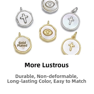 Détail macro de pendentifs croix et œil maléfique plaqués or 18 carats avec nacre