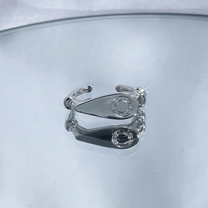 Macro shot of silver teardrop ear cuff with metallic finish on a reflective mirror