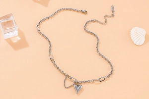 Détail macro du collier coeur en acier titane argenté avec maillons de chaîne mixtes