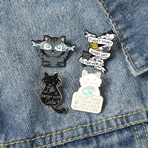 Set of 4 cute enamel cat pins with inspirational quotes on blue denim jacket fabric