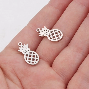 Detailed view of silver hollow pineapple charms for DIY jewelry held in a person's hand