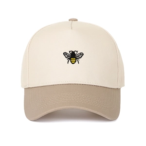 Detailed embroidery of a black and yellow bee on a two-tone beige and khaki baseball cap