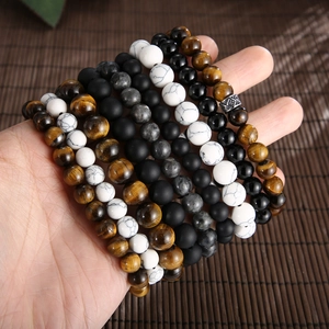 Beaded bracelets set with tiger eye, turquoise, and onyx stones on a person's wrist