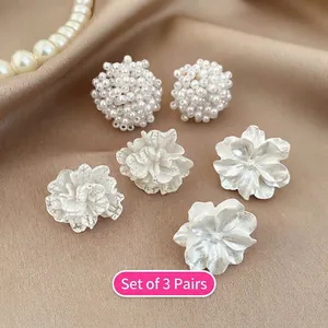 Detailed view of 3-pair earring set with pearls and floral studs on champagne silk