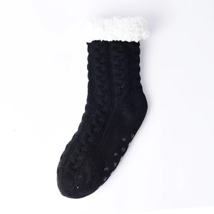 Detailed view of black knitted slipper socks with white faux fur cuff and non-slip sole dots