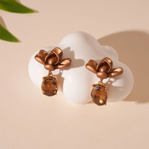 Detail shot of vintage bronze flower earrings with amber zircon drop on cloud display