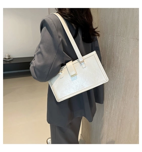 Side view of white rectangular shoulder bag with metal buckle on a female model